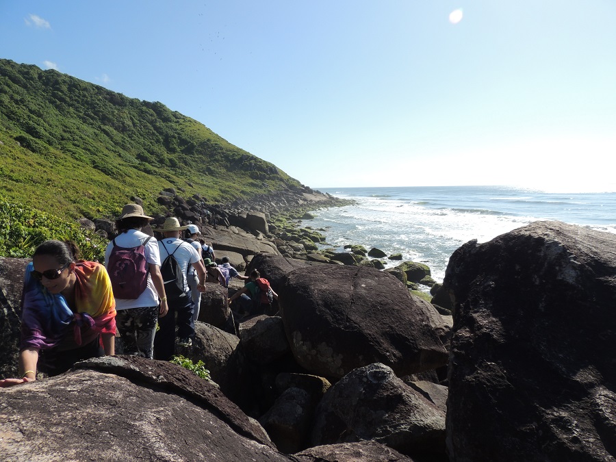 imagem-de-turistas-caminhando-nas-rochas-da-praia
