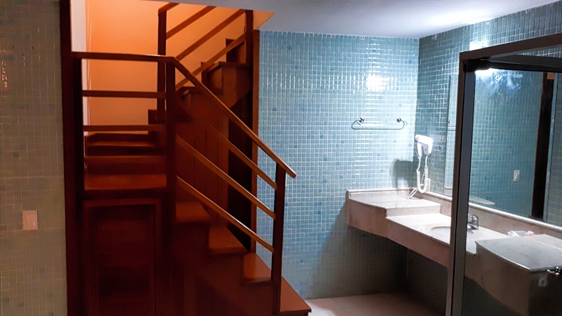 foto-mostra-escada-de-madeira-que-leva-ao-andar-inferior-da-suite-onde-se-encontra-a-banheira-de-hidromassagem-e-um ôfuro