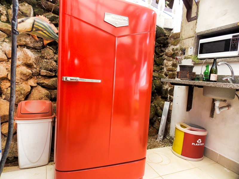 foto-demonstra-uma-grande-geladeira-vermelha-antiga-muito-bem-conservada-e-um-espaço-para-uso-com-microondas-e-fogão