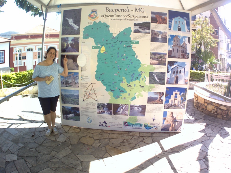 foto-mostra-pessoa-mostrando-painel-que-indica-atrativos-turísticos-da-cidade- baependi-mg-a-cidade-da-aventura-e-do-turismo-religioso